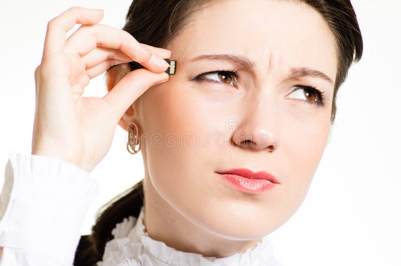 Pretty girl plugging micro SD memory stick to her head closeup portrait over white background. Pretty girl plugging micro SD memory stick to her head closeup portrait over white background