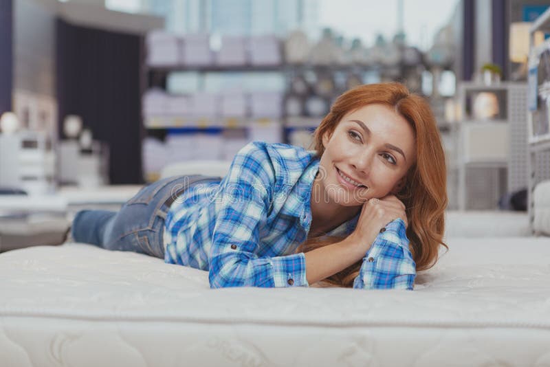 Mooie vrouw die nieuwe matras kopen bij meubilairopslag royalty-vrije stock afbeelding Mooie vrouw die nieuwe matras kopen bij meubilairopslag royalty-vrije stock afbeelding