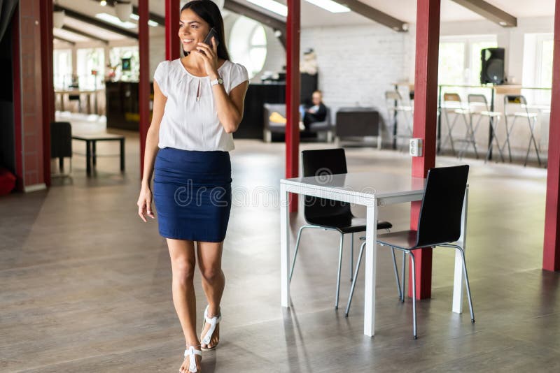 Mooie Vrouw die op Telefoon spreken die in Bureau lopen Portret van Modieuze Glimlachende Bedrijfsvrouw in Modieuze Kleren stock afbeelding Mooie Vrouw die op Telefoon spreken die in Bureau lopen Portret van Modieuze Glimlachende Bedrijfsvrouw in Modieuze Kleren stock afbeelding