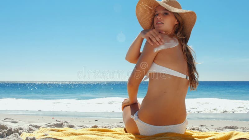 Mooie vrouw die op zonnescherm bij strand zetten