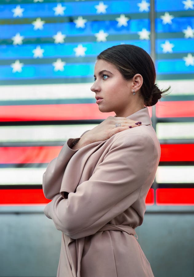 Mooie vrouw die zich voor Amerikaanse vlag bevinden en aan de kant kijken Het patriottismeconcept van de mensennatie royalty-vrije stock foto Mooie vrouw die zich voor Amerikaanse vlag bevinden en aan de kant kijken Het patriottismeconcept van de mensennatie royalty-vrije stock foto