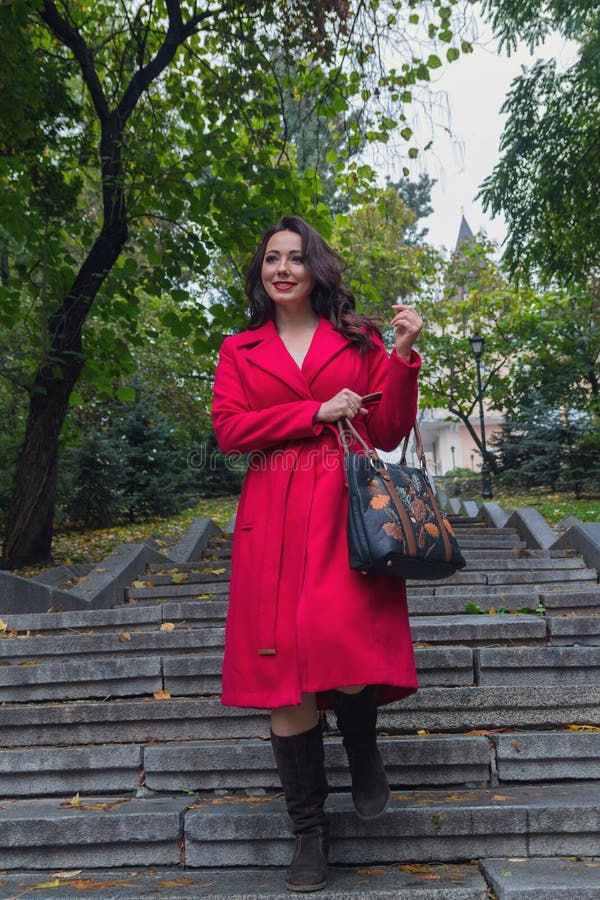 Mooie vrouw in een rode laag die onderaan de treden lopen royalty-vrije stock foto's Mooie vrouw in een rode laag die onderaan de treden lopen royalty-vrije stock foto's