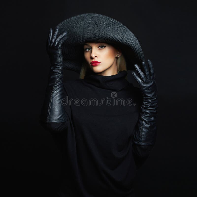 Mooie vrouw in hoed en leerhandschoenen mannequinmeisje die zwarte hoed proberen De heks van Halloween royalty-vrije stock foto Mooie vrouw in hoed en leerhandschoenen mannequinmeisje die zwarte hoed proberen De heks van Halloween royalty-vrije stock foto