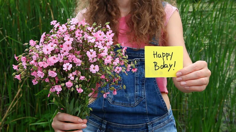 Mooie vrouw met Gelukkige verjaardagskaart en roze bloemen