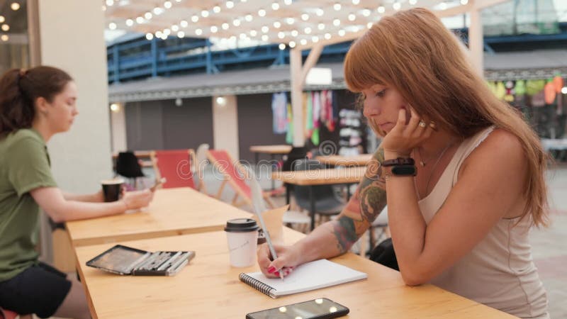 Mooie vrouw met tatoeages in een laptop. real time. recreatie op het terras in een café