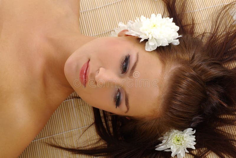 Portrait of Fresh and Beautiful woman laying on bamboo mat around flowers and taking spa treatment. Portrait of Fresh and Beautiful woman laying on bamboo mat around flowers and taking spa treatment