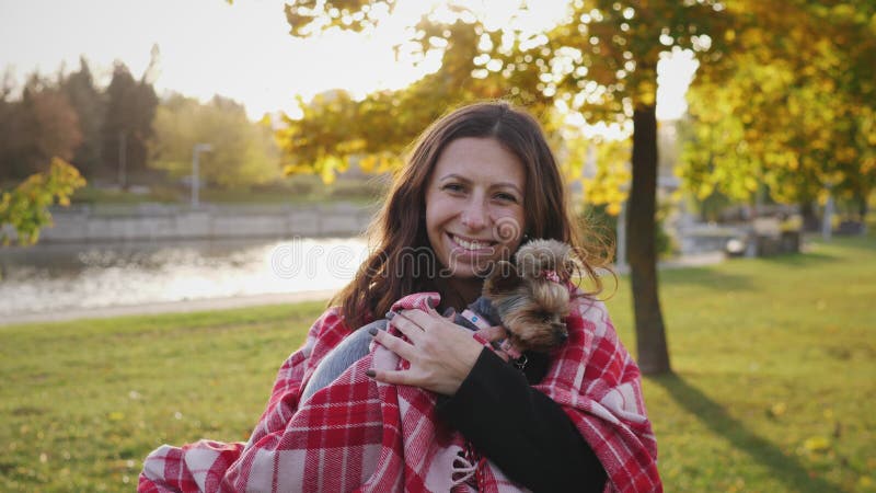 Mooie vrouw portretteert glimlachen en houdt haar kleine yorkie hond vast