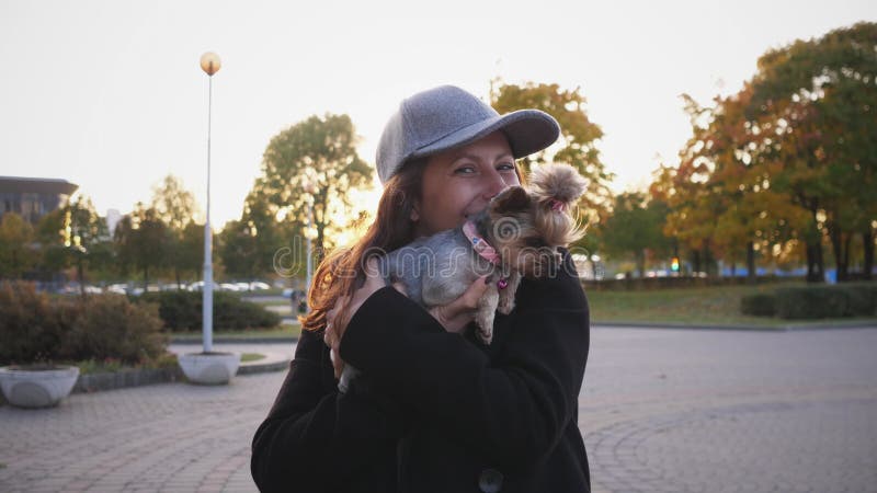 Mooie vrouw portretteert glimlachen en houdt haar kleine yorkie hond vast