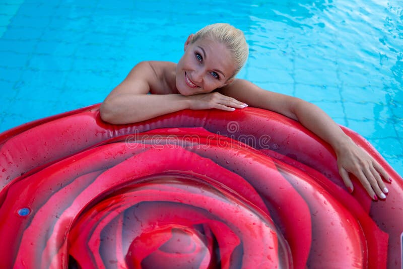 Mooie vrouw zwemt op een luchtmatras in de vijver van een mooi hotel stock foto Mooie vrouw zwemt op een luchtmatras in de vijver van een mooi hotel stock foto