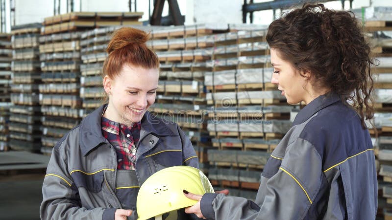 Mooie vrouwelijke fabrieksarbeider die een bouwvakker van haar collega ontvangen stock fotografie Mooie vrouwelijke fabrieksarbeider die een bouwvakker van haar collega ontvangen stock fotografie