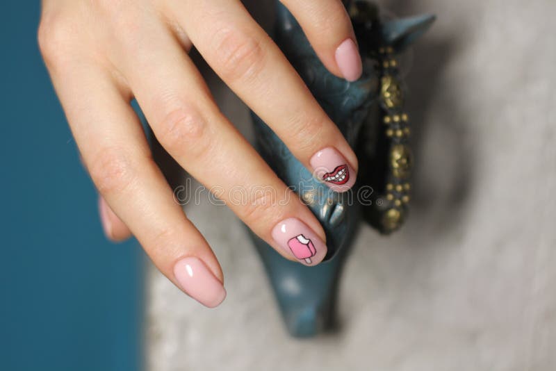 Mooie vrouwelijke hand met manicure Lichtrose nagellak met creatief ontwerp Lippen en roomijsstickers royalty-vrije stock afbeeldingen Mooie vrouwelijke hand met manicure Lichtrose nagellak met creatief ontwerp Lippen en roomijsstickers royalty-vrije stock afbeeldingen