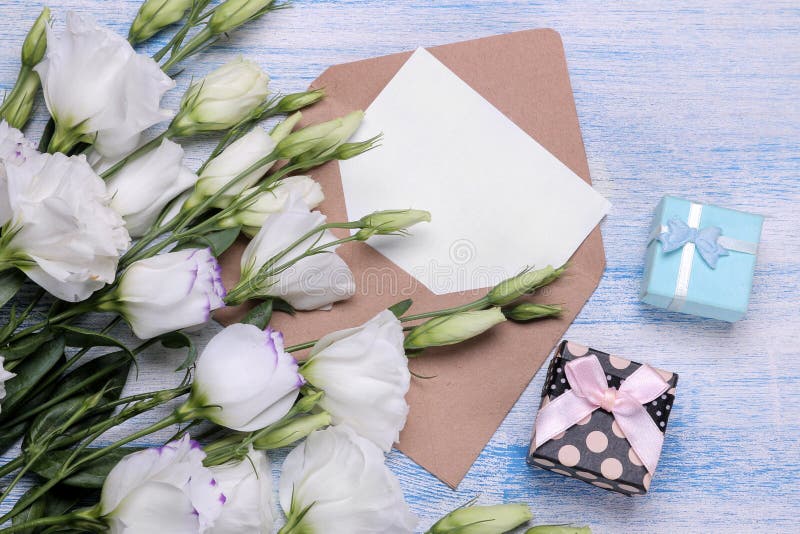 Mooie witte bloemen Eustomaboeket met giften, een envelop en een spatie voor tekst op een blauwe houten lijst Mening van hierbove royalty-vrije stock foto Mooie witte bloemen Eustomaboeket met giften, een envelop en een spatie voor tekst op een blauwe houten lijst Mening van hierbove royalty-vrije stock foto
