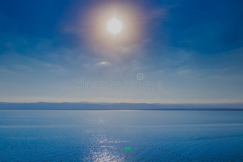Mooie zonsondergang bij Dode Overzeese kustlijn in Jordanië, het schitteren van zonneschijn in water stock fotografie Mooie zonsondergang bij Dode Overzeese kustlijn in Jordanië, het schitteren van zonneschijn in water stock fotografie