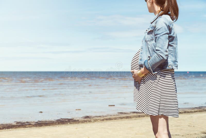 Mooie zwangere vrouw die zich op het strand bevinden Zwangere vrouw die een gang nemen door het strand royalty-vrije stock foto's Mooie zwangere vrouw die zich op het strand bevinden Zwangere vrouw die een gang nemen door het strand royalty-vrije stock foto's