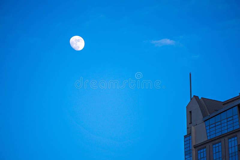 Moon hovering over high rise building in the city stock image Moon hovering over high rise building in the city stock image