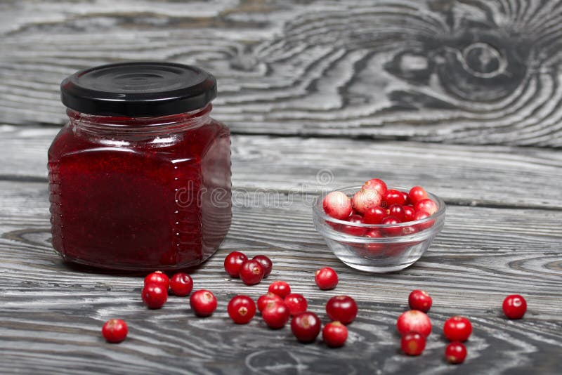 Moosbeermarmelade in Glasgefäßen Verschließen Sie gelegene Beeren sind in einem Repository und verstreut über die Oberfläche Auf Holz Vorstände mit einer schönen Art