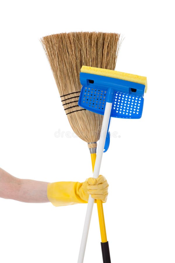 A yellow gloved hand holding a sponge mop and a corn or straw broom on a white background. Household chores concept. A yellow gloved hand holding a sponge mop and a corn or straw broom on a white background. Household chores concept.