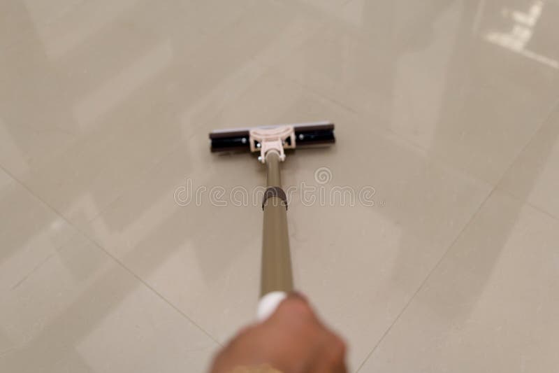Mop Portabil Care Curăță Suprafața Netedă A Podelei. Strângerea unei mâini folosind un mop pentru curățarea unei podele lucioase, care subliniază curățenia și treburile casnice. Ideale pentru teme legate de menaj sau servicii de curățenie