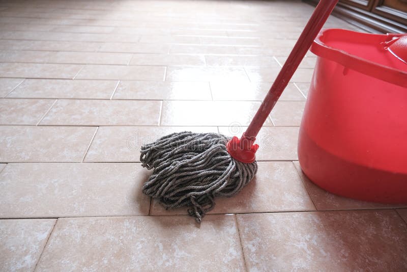 Mop and red bucket of cleaning on the tiled floor ready to clean close-up.  Cleaning services. Home interior