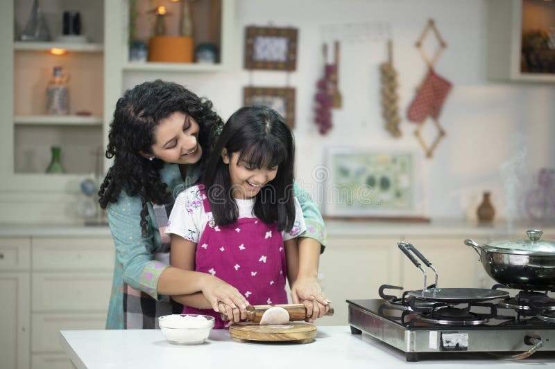 Mor dotters matlagning av chapati indian bröd arkivfoton