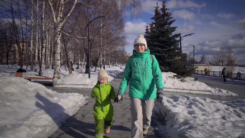 Mor och barn som håller hand går genom vinterparken