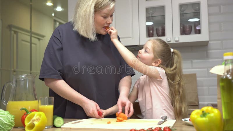 Mor och dotter förbereder glatt sallad i ett mysigt kök stock video