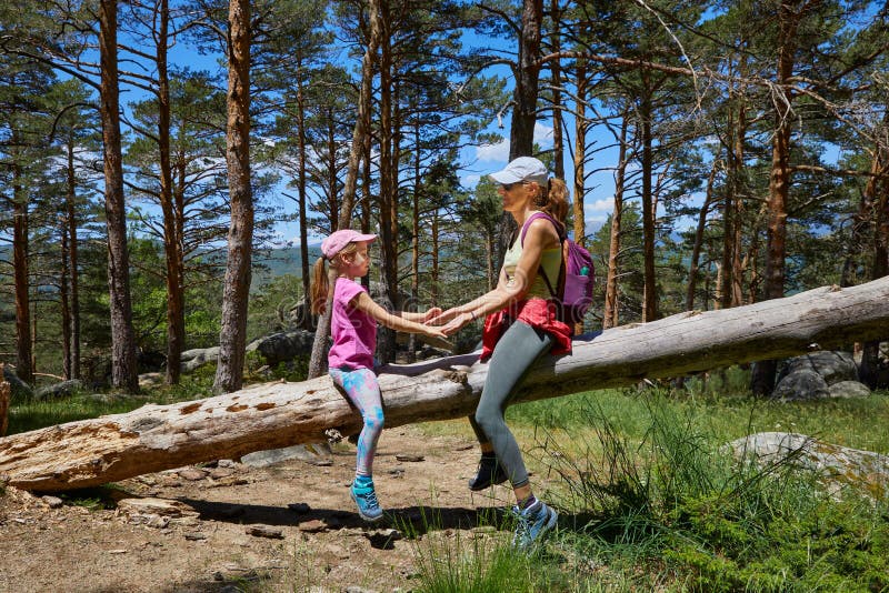 Mor och dotter leker på trädrunken i en skog arkivfoto