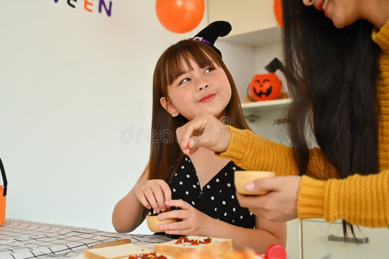 Mor och dotter som dekorerar halloween cupcakes i det dekorerade köket royaltyfria bilder