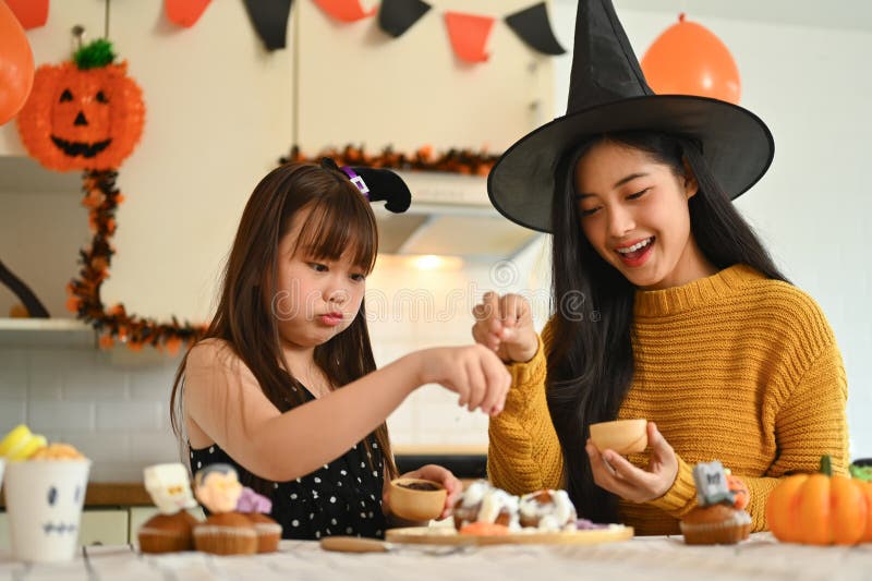 Mor och dotter som dekorerar halloween cupcakes i det dekorerade köket royaltyfri fotografi