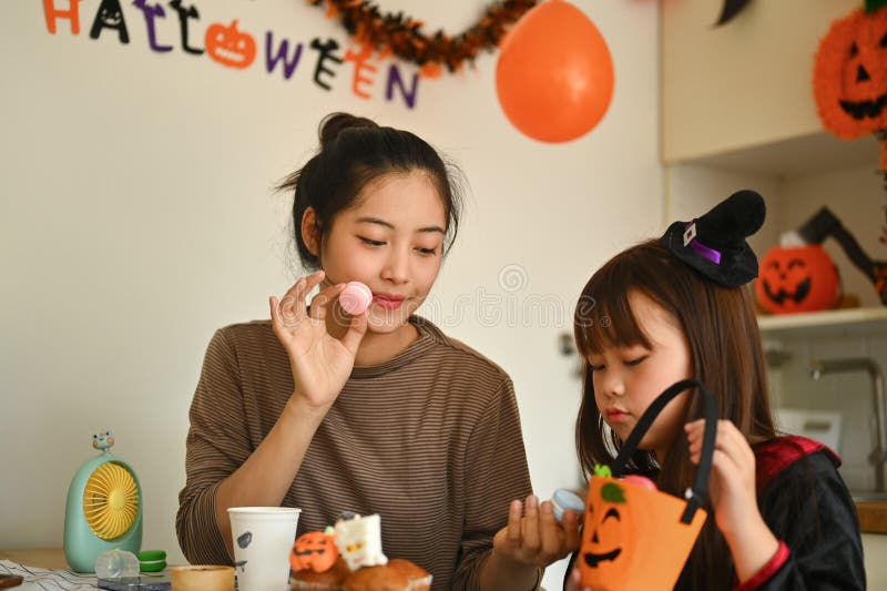Mor och dotter som dekorerar halloween cupcakes i det dekorerade köket royaltyfria bilder