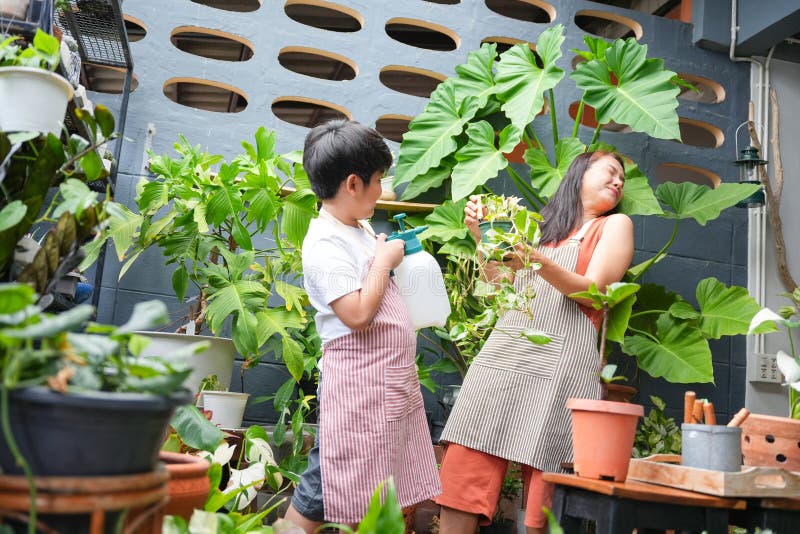 Mor- och Son-bindning över trädgårdsskötsel i hemmet, barn hjälper mamma vattenväxter i Urban Garden A Young Boy och royaltyfri foto