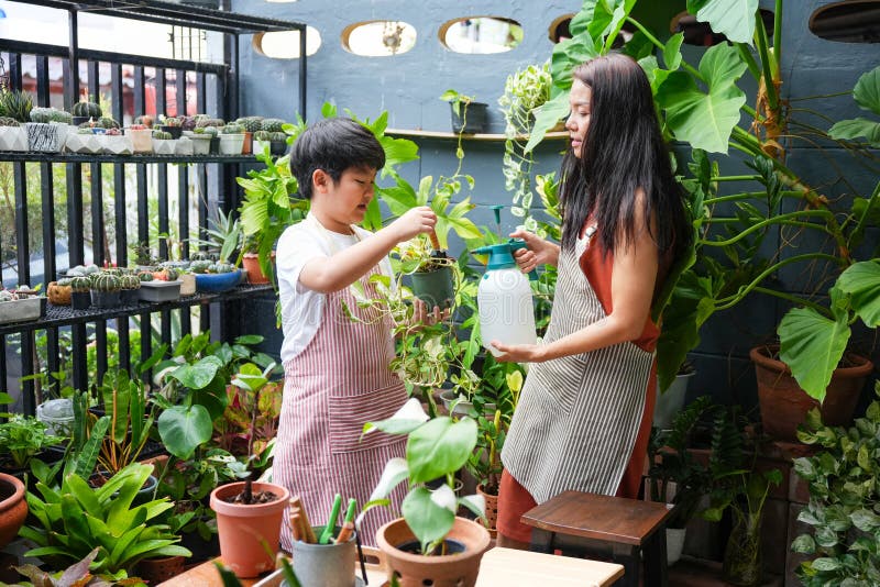 Mor och son Gardening tillsammans i hemmet Joyful Family Moment Child hjälper Mor Water Plants i Urban Garden A Young Boy och hans royaltyfria foton