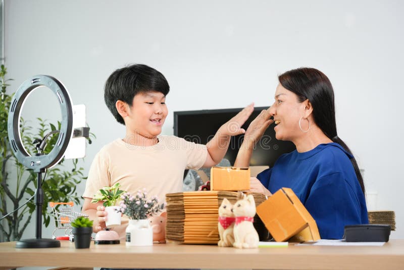 Mor och son som skapar onlineinnehåll för onlineförsäljning från Home Glad Asian Family Packing Orders for Ecommerce Joyful Mamma royaltyfri bild