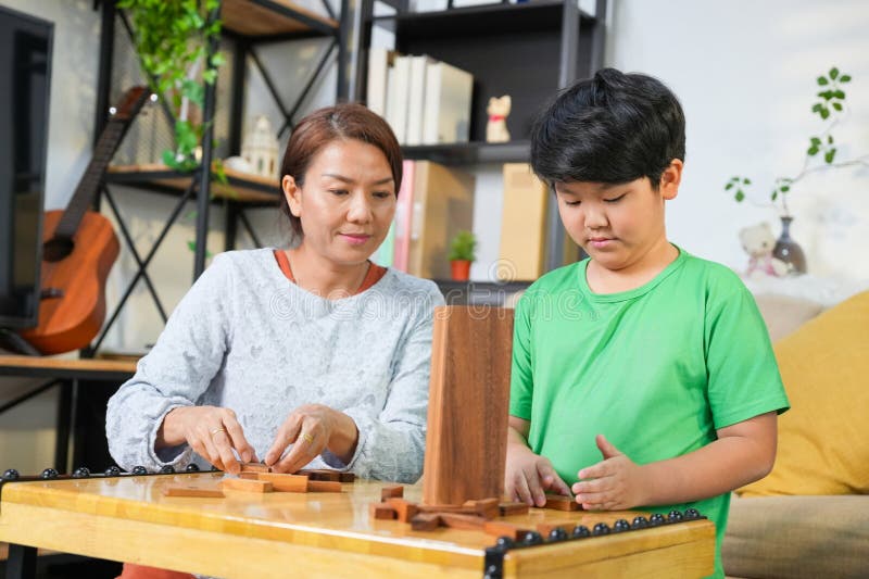 Mor och son spelar blockspel i bostadsrummet Glad asiatisk familjerelation med FoR-föräldrar och barn inom spelet. arkivfoton