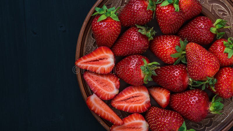 Morangos frescas em uma placa em uma tabela de madeira imagem de stock royalty free