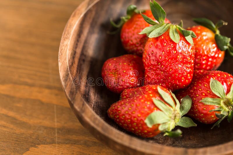 Morangos em tigela de madeira imagem de stock