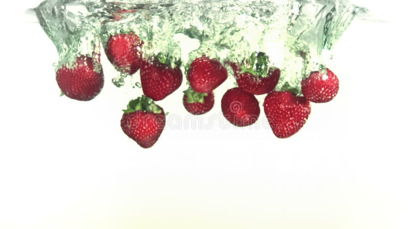 Morangos vermelhos a cair na água em super câmara lenta filme