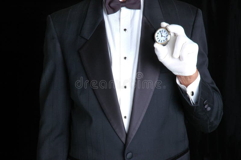 Butler in Tuxedo Holding a Pocket Watch with the Face pointing towards camera. Butler in Tuxedo Holding a Pocket Watch with the Face pointing towards camera