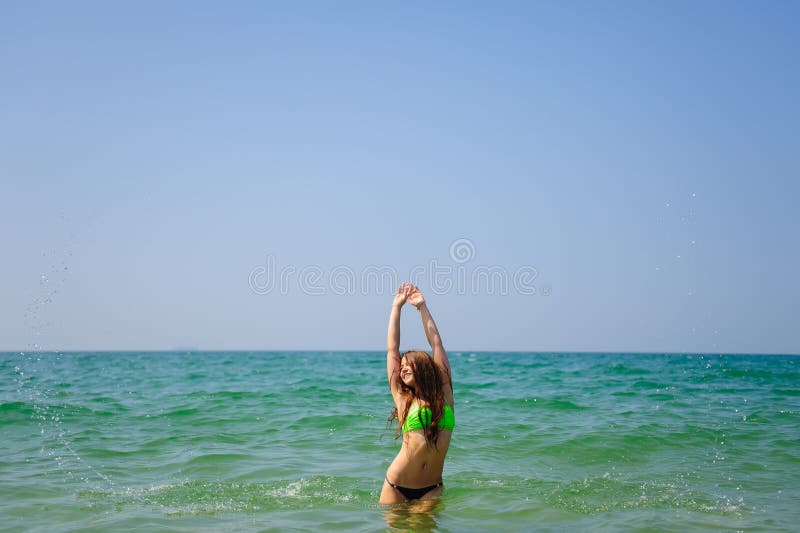 Morena bonita com suportes longos do cabelo no mar que levanta suas mãos e para enfrentar ao sol e ao céu Menina tanned nova foto de stock royalty free Morena bonita com suportes longos do cabelo no mar que levanta suas mãos e para enfrentar ao sol e ao céu Menina tanned nova foto de stock royalty free