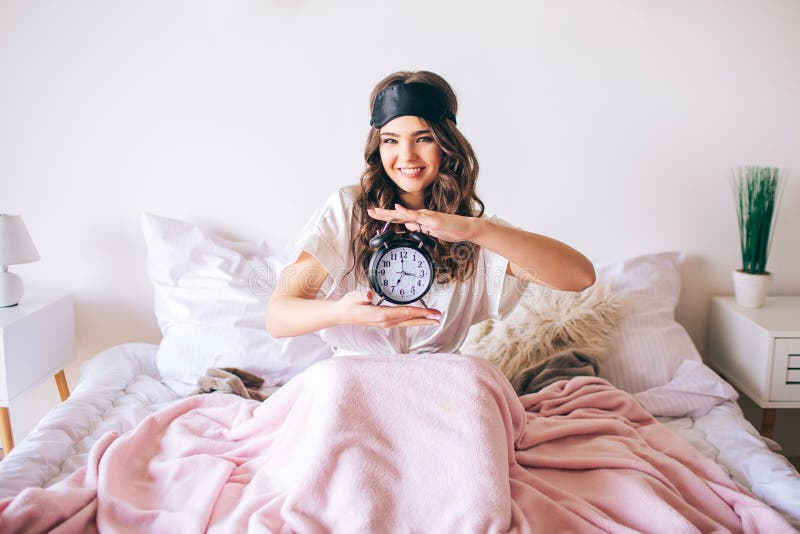 Morena nova bonita de cabelo escura para acordar em sua cama Pulso de disparo agradável alegre da terra arrendada da mulher nas m fotos de stock Morena nova bonita de cabelo escura para acordar em sua cama Pulso de disparo agradável alegre da terra arrendada da mulher nas m fotos de stock