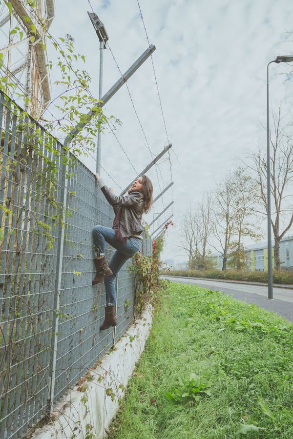 Uma jovem morena bonita a escalar uma cerca imagens de stock royalty free