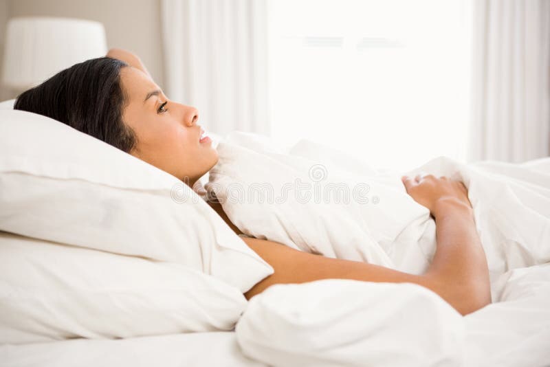 Morena olhando de sobrancelhas franzidas na cama foto de stock royalty free Morena olhando de sobrancelhas franzidas na cama foto de stock royalty free
