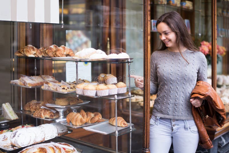 Portrait of happy brunette looking at fancy cakes in bakery. Portrait of happy brunette looking at fancy cakes in bakery