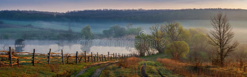 Morgen im ukrainischen Dorf, bedeckt mit Nebel nahe dem See lizenzfreies stockbild Morgen im ukrainischen Dorf, bedeckt mit Nebel nahe dem See lizenzfreies stockbild