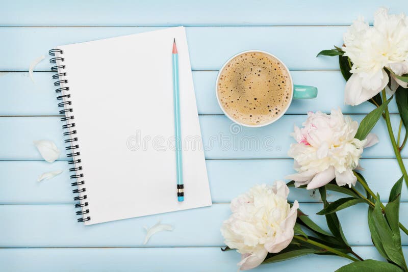 Morning coffee mug, empty notebook, pencil and white peony flowers on blue wooden table, cozy summer breakfast, top view. Morning coffee mug, empty notebook, pencil and white peony flowers on blue wooden table, cozy summer breakfast, top view