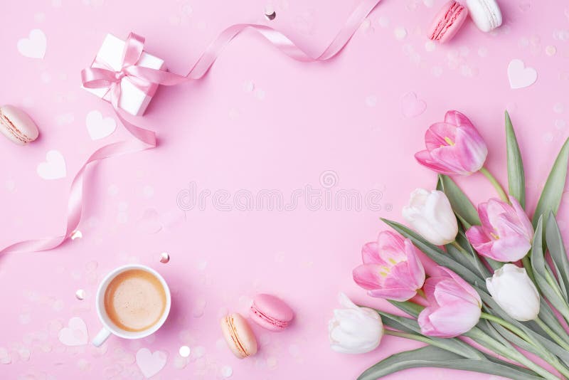 Morning cup of coffee, cake macaron, gift or present box and spring tulip flowers on pink background. Beautiful breakfast for Women day, Mother day. Flat lay. Morning cup of coffee, cake macaron, gift or present box and spring tulip flowers on pink background. Beautiful breakfast for Women day, Mother day. Flat lay