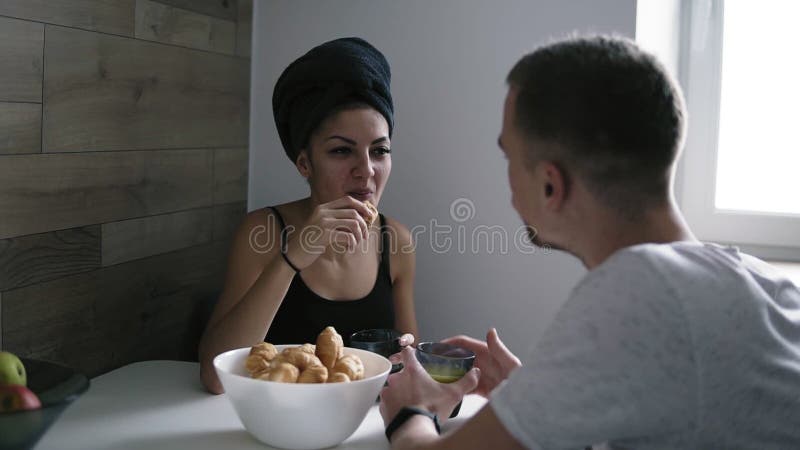 Morgon av de lyckliga härliga unga paren som ler, talar och dricker kaffe med giffel under frukosten