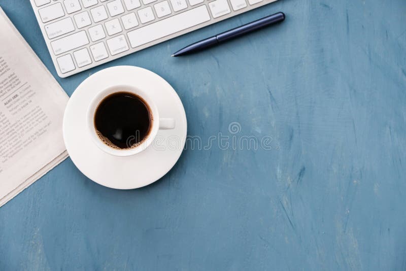 Morning coffee and fresh newspaper on the blue desk top