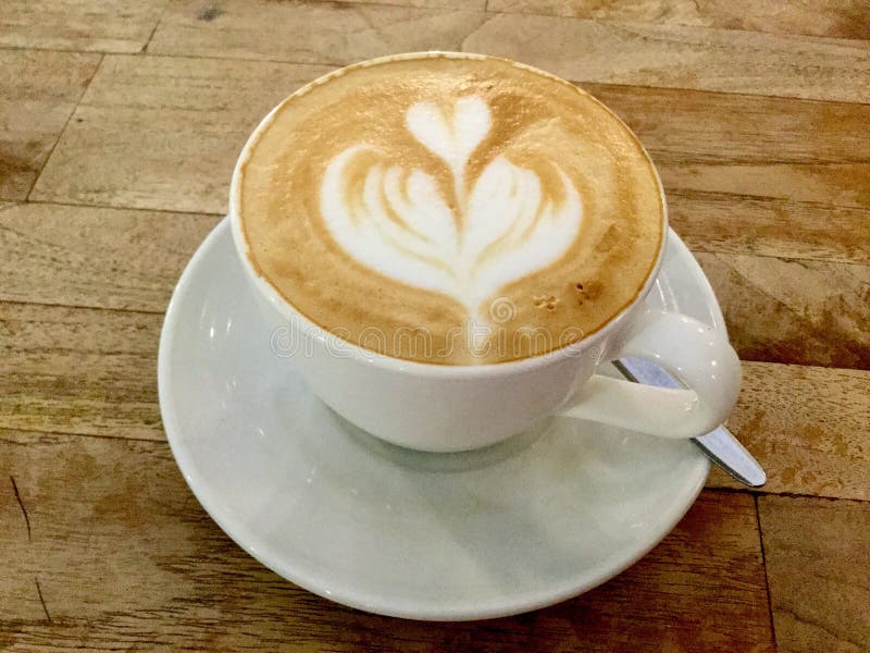 Morning coffee on Wooden table. Cappuccino art. Classic.