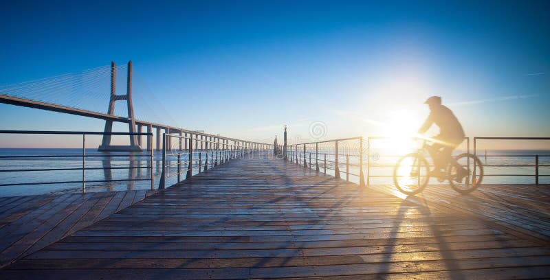 Man riding a bicycle in a riverside boardwalk. Boardwalk rail stock images, royalty-free photos and pictures